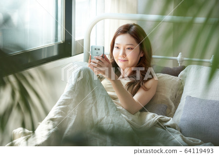 Young woman window bedroom relaxing morning call Young woman window bedroom relaxing morning call 64119493