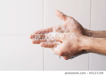 Man cleaning his hands using liquid disinfectant soap. 64121194