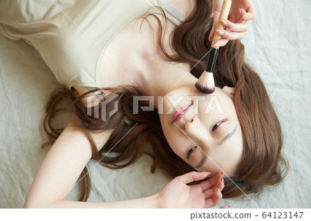 Young woman morning bed makeup skin care Young woman morning bed makeup skin care 64123147