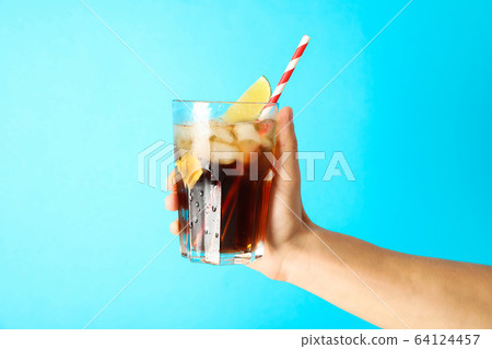 Female hand holding a glass with ice cola, tubule Female hand holding a glass with ice cola, tubule 64124457