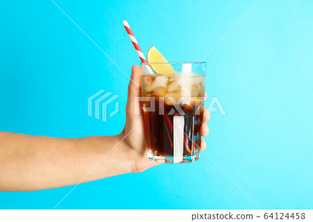 Female hand holding a glass with ice cola, tubule Female hand holding a glass with ice cola, tubule 64124458