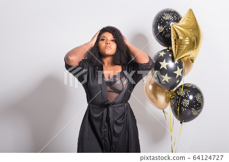 Holidays, birthday party and fun concept - Portrait of smiling young African-American young woman looking stylish on white background holding balloons. 64124727
