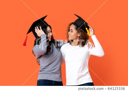 Portrait of two happy mixed-race women graduating 64125336
