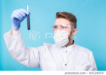 Covid-19, coronavirus, Vaccine development, pandemic and outbreak concept - Man scientist in flu mask and protective gloves holding a test tube. Covid-19, coronavirus, Vaccine development, pandemic and outbreak concept - Man scientist in flu mask and protective gloves holding a test tube. 64126059