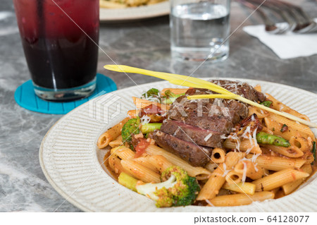 Macaroni with steak and tomato sauce on the table. Macaroni with steak and tomato sauce on the table. 64128077