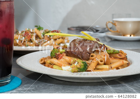 Macaroni with steak and tomato sauce on the table. 64128082
