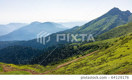 Green mountain slope. Layers of mountains in the haze 64129176