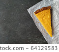 A piece of pumpkin cheesecake on white crumpled paper on a black granite chalkboard with text space 64129583
