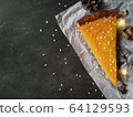 A piece of pumpkin cheesecake on white crumpled paper on a black granite chalkboard with text space 64129593