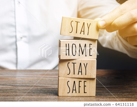 Man puts wooden blocks with the words Stay home stay safe. The concept of prevention from coronavirus infection. Self-isolation and quarantine. COVID-19, ncov 64131118