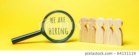 A magnifying glass with the word We are hiring and a crowd of people. Employee Search. Attraction to work. Human Resource Management. Hire. Promotion. Working staff. Business concept 64131119