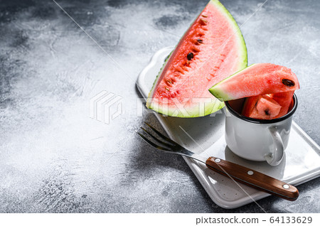 Slices of ripe watermelon on a white cutting Board. Gray background. Space for text 64133629