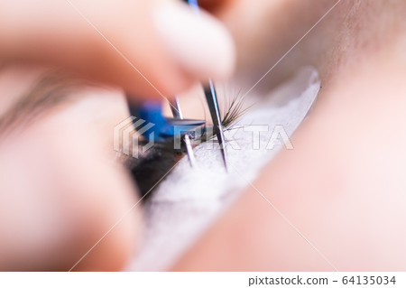 Eyelash Extension Procedure. Woman Eye with Long Eyelashes. Lashes, close up, macro, selective focus. 64135034