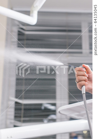 Dentistry, dental health and medicine concept - Close-up of dentist's hand holding a dental tool instrument. Dentistry, dental health and medicine concept - Close-up of dentist's hand holding a dental tool instrument. 64135045