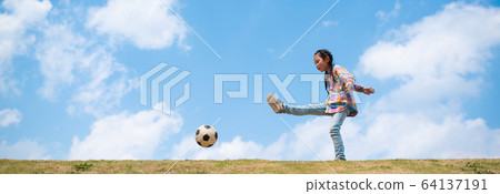 Girl kicking a soccer ball under the blue sky 64137191