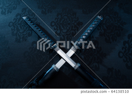 Two katanas with partially drawn blades on fabric 64138510