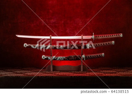 Three swords on stand, katana blade exposed, red 64138515
