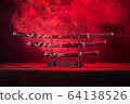 Three swords on stand, red smoke behind 64138526