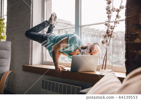 Young man doing yoga at home while being quarantine and freelance working Young man doing yoga at home while being quarantine and freelance working 64139553