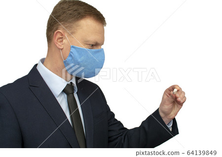 Businessman man in a medical mask looks at a thermometer. Businessman man in a medical mask looks at a thermometer. 64139849