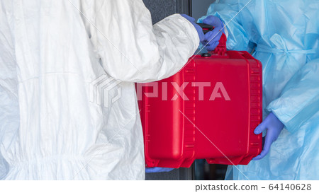 A courier in a protective suit hands the doctor a red case with valuable medicines 64140628