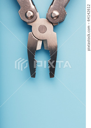 Multifunctional tool close-up on a blue background. The concept of a pocket tool with free space. Multifunctional tool close-up on a blue background. The concept of a pocket tool with free space. 64142612