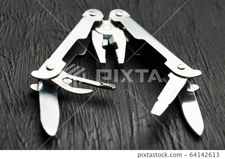 Multi-functional tool on a black textural background. Multi-functional tool on a black textural background. 64142613