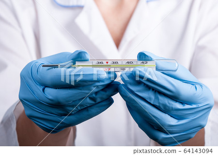 Doctor's hand in a bkue gloves holding thermometer indicating a high temperature 64143094