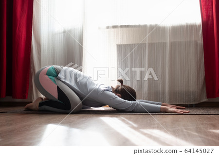 woman doing Child pose, Balasana, studio full length at the living room woman doing Child pose, Balasana, studio full length at the living room 64145027