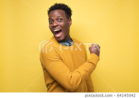 Happy successful african american young student showing fist Happy successful african american young student showing fist 64145042