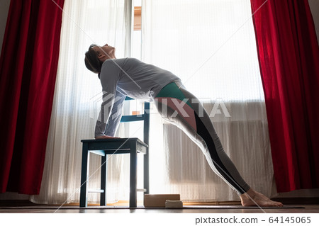 Woman practicing yoga indoors at home doing Upward Plank Pose 64145065