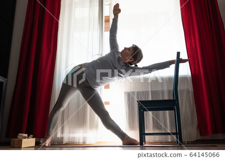 Sporty attractive young woman doing side bend, Trikonasana posture 64145066