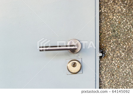 Mortise lock with a knob and keyhole on a metal door painted in gray. 64145092