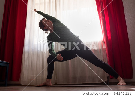 woman student doing utthita parsvakonasana at the living room at home. 64145135