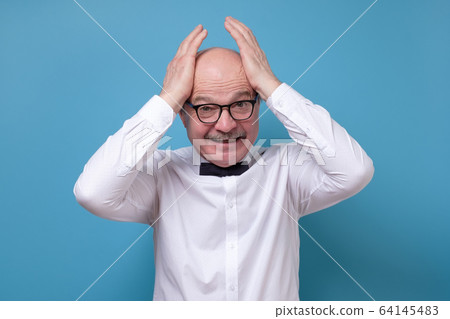 Stressful senior male screams in panic, keeps hands on head 64145483