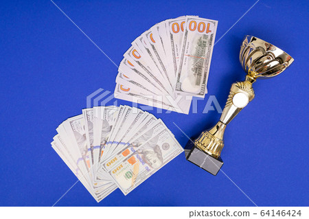heap of money and winner cup on pure blue table background 64146424