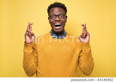 African american man crossing fingers wishing and praying for miracle African american man crossing fingers wishing and praying for miracle 64146992