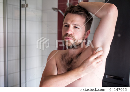shirtless caucasian man putting deodorant in the bathroom shirtless caucasian man putting deodorant in the bathroom 64147033