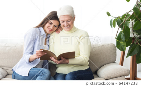 Happy mother and daughter looking family photo album 64147238