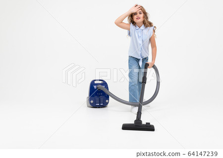 teen girl vacuuming the floor with a vacuum cleaner on an isolated white background with copy space 64147239