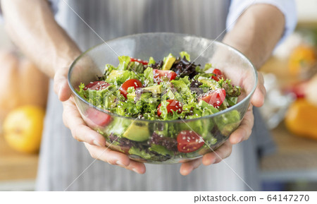 Man holding full bowl of fresh green salad, panorama 64147270