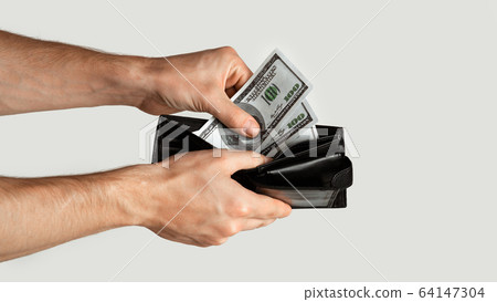 Unrecognizable young man taking dollars from wallet on white background, empty space. Panorama Unrecognizable young man taking dollars from wallet on white background, empty space. Panorama 64147304