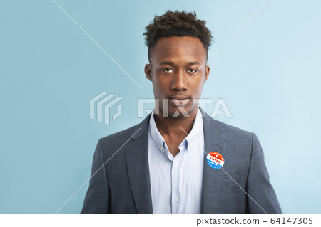 African american politician in suit with pinned vote button on blue African american politician in suit with pinned vote button on blue 64147305