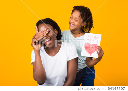 Black girl congratulating her mom isolated at yellow studio Black girl congratulating her mom isolated at yellow studio 64147307
