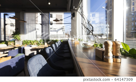 Sunny morning in modern cafe with big panoramic windows Sunny morning in modern cafe with big panoramic windows 64147309