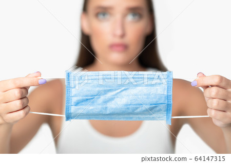 Girl Showing Protective Medical Mask On White Background, Shallow Depth Girl Showing Protective Medical Mask On White Background, Shallow Depth 64147315