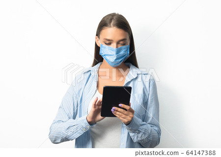 Woman In Face Mask Using Tablet Computer On White Background 64147388