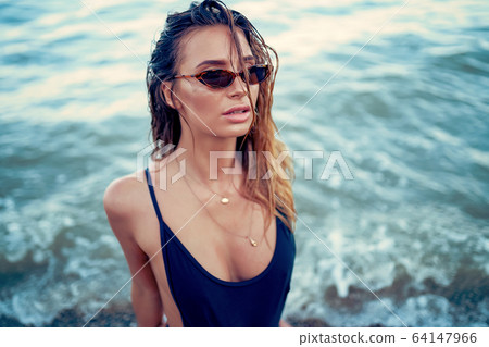 portrait of beautiful sexy caucasian sunbathed woman in leopard print sunglasses with long hair in swimsuit lying on summer beach 64147966