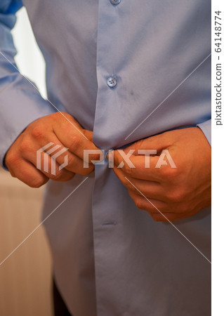 Close-up of a man in a closing the buttons of the shirt of his suit Close-up of a man in a closing the buttons of the shirt of his suit 64148774