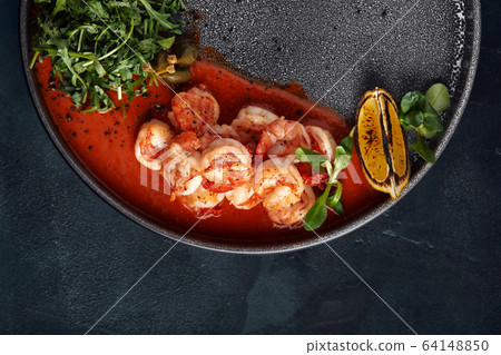 Grilled tiger crackers beautifully canned on a plate with tomato sauce and arugula, Mediterranean food concept, Food photo. Top view, blue background, copy space 64148850